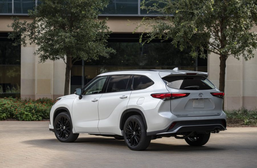 A pearl white 2023 Toyota Highlander parked outside in left rear angle view