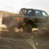 A 2024 Ford F-150 Raptor, one of the Ford F-Series lineup of best-selling pickup truck models in America, kicks up sand.