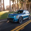 A blue 2024 Kia EV9 driving on a road in left front angle view