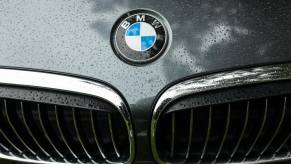 The BMW logo and kidney grille of a 550i sedan covered in rain.