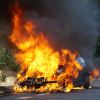 A car burned next to a building.