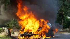 A car burned next to a building.