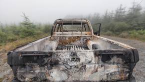 Burned out pickup truck parked in the forest.