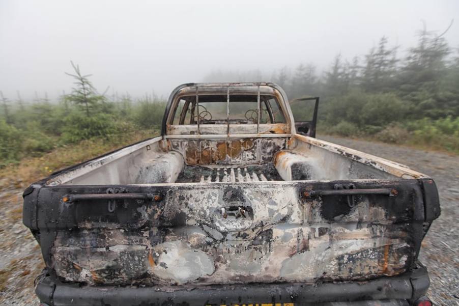 Burned out pickup truck parked in the forest.