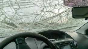 Broken car windshield visible over the steering wheel after a crash.