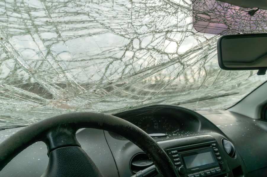 Broken car windshield visible over the steering wheel after a crash.