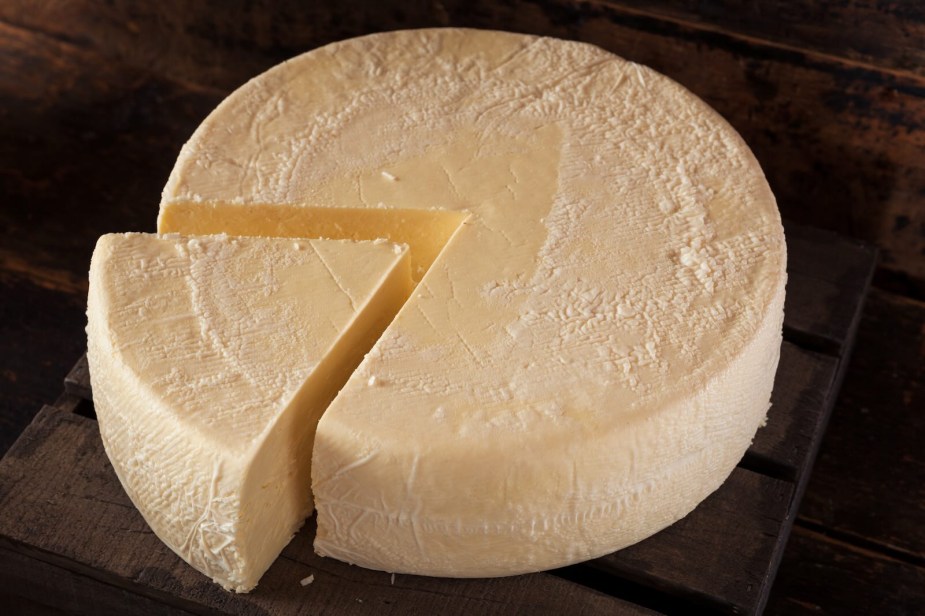 Full wheel of cheese on a black background.