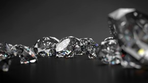 Closeup of an assortment of cut diamonds on a dark background.