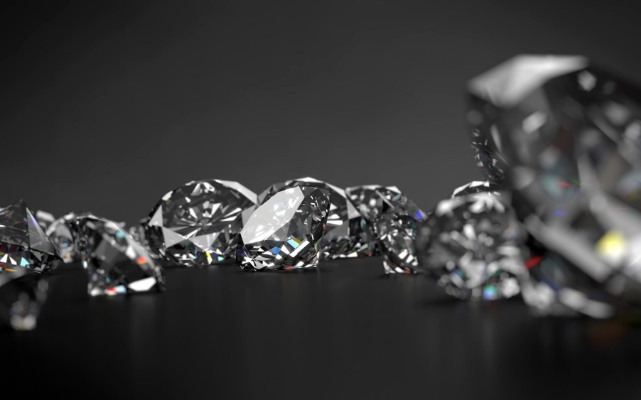 Closeup of an assortment of cut diamonds on a dark background.