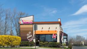 Tan Dunkin Donuts restaurant franchise, a blue sky visible in the background.