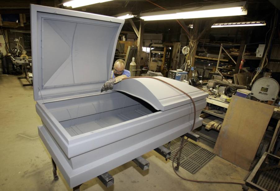 Casket maker shapes an extra-large 48-inch casket out of steel in a workshop.