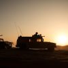 A set of military vehicles against a backdrop of a setting sun.