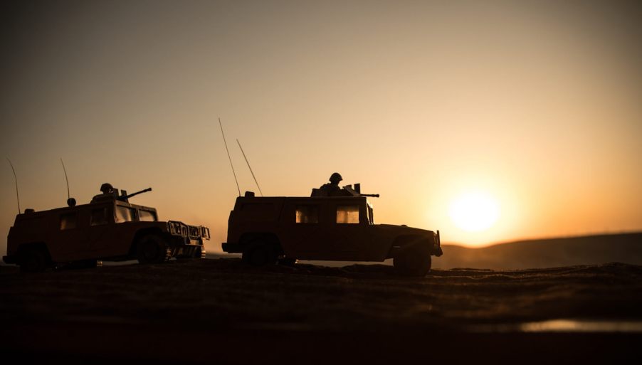 A set of military vehicles against a backdrop of a setting sun.