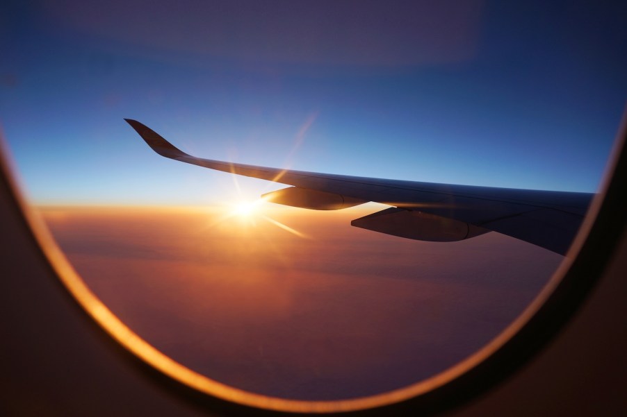 Window of a commercial jet airliner, the sunset visible in the background.