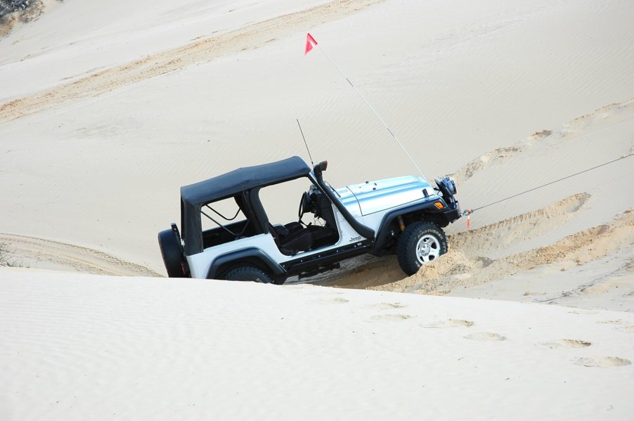 A Jeep Wrangler TJ in the sand after a jump.