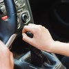 Woman's hand on the gearshift lever of a manual stick shift transmission.