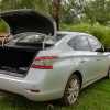 Silver Nissan car with its trunk popped open.