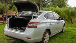 Silver Nissan car with its trunk popped open.