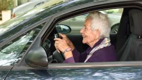 An elderly driver sits up close to the steering wheel.