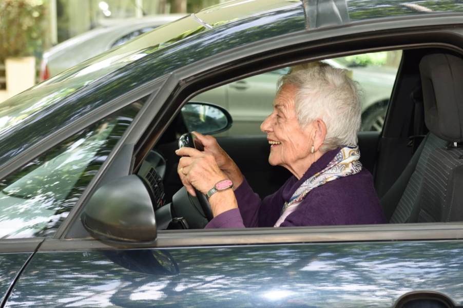 An elderly driver sits up close to the steering wheel.