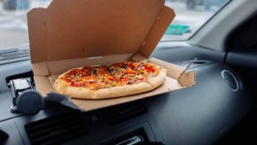 Box of pizza on the dashboard of a Honda fit car