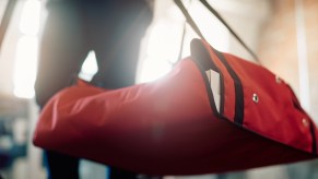 man carries red pizza delivery bag into a house.