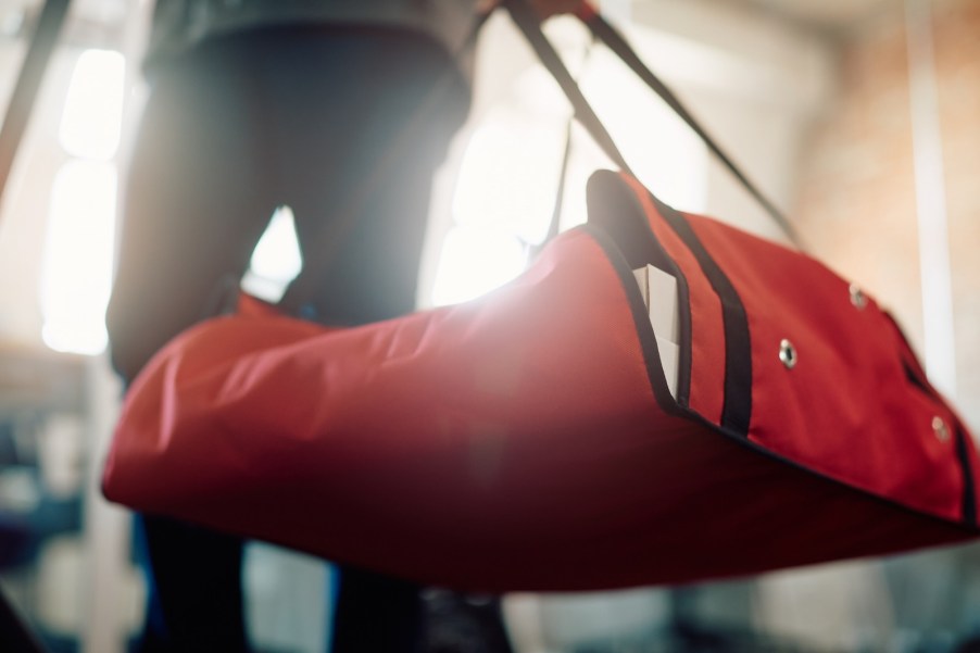 man carries red pizza delivery bag into a house.