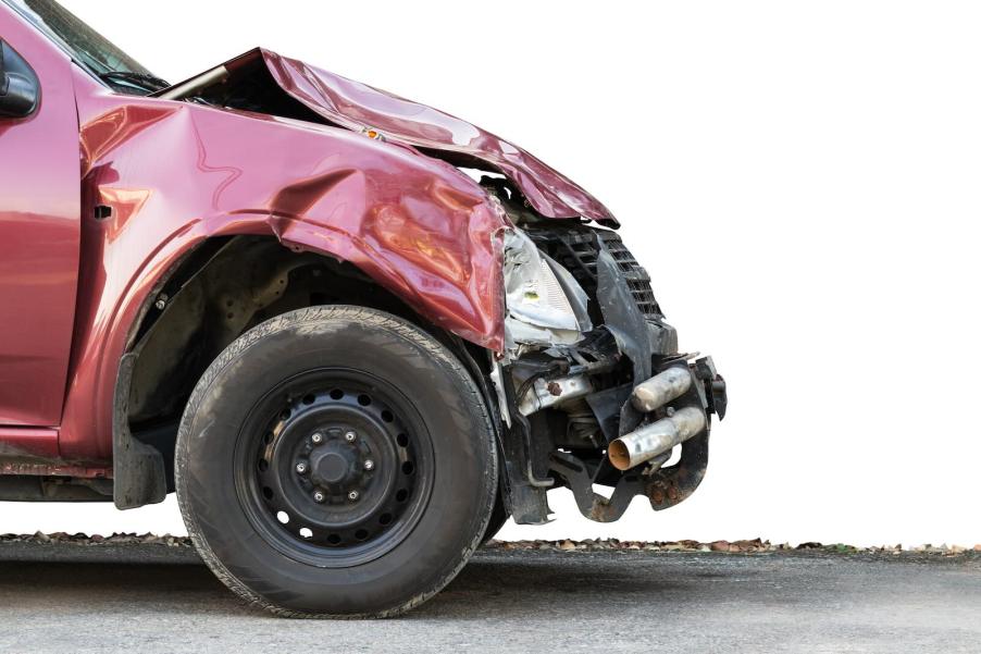 Front bumper of a red pickup truck, smashed by a crash.