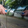 A car is vandalized with a screwdriver.