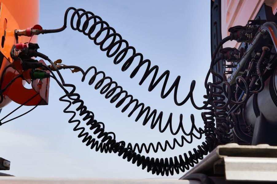 A series of cables and hoses between a semi truck cab and trailer.