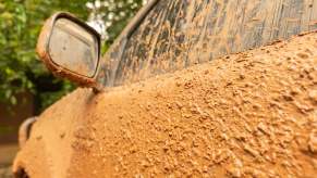 Car door coated with brown mud.