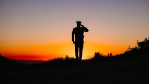 Police officer standing in front of the setting sun.