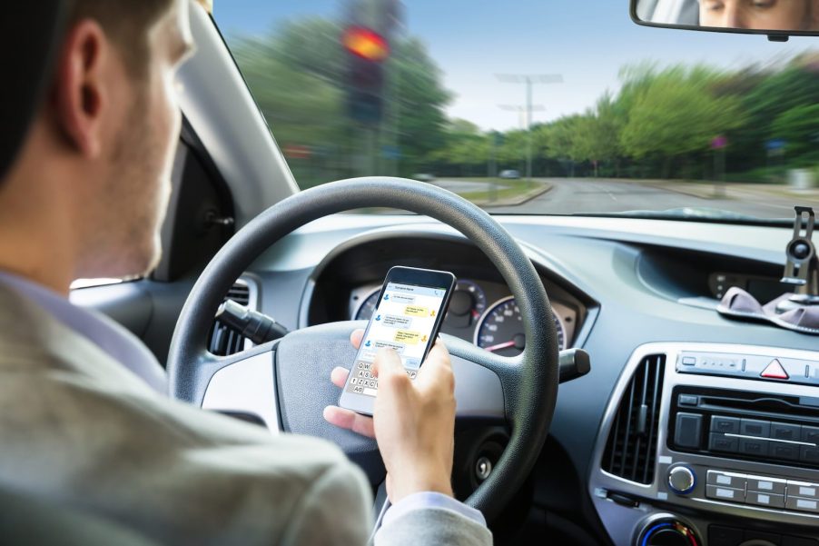 Man texts on his phone while parked at a stoplight.