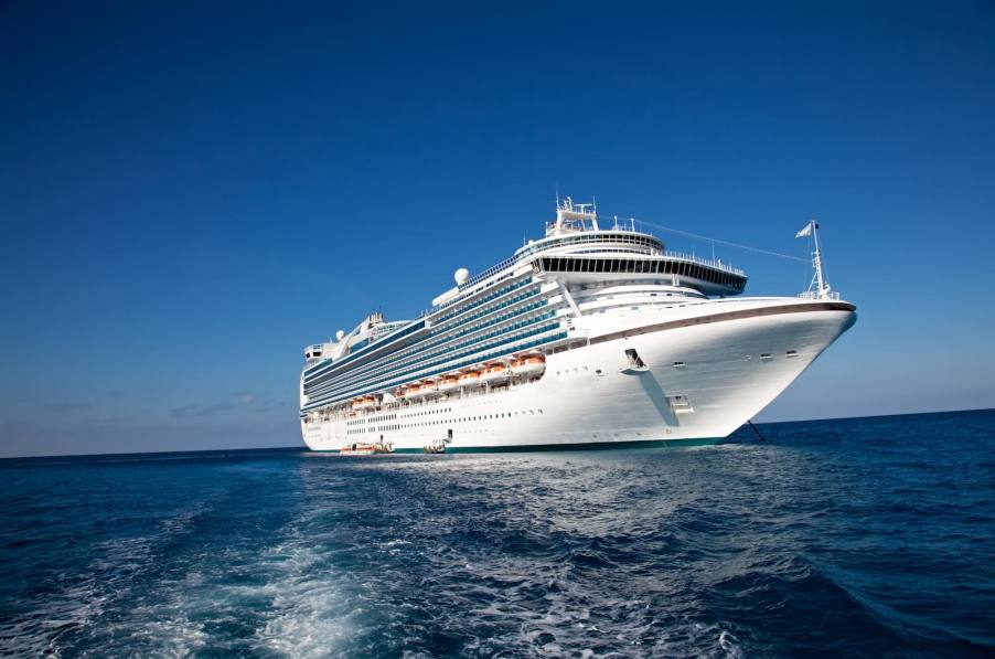 White luxury cruise ship floats on a bright blue ocean.