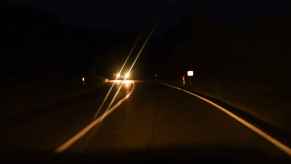 Driving on a highway at night facing blurred headlights on an opposing oncoming vehicle