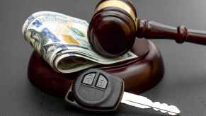 Depiction of attorney car insurance judgement using a gavel with folded paper money and car key