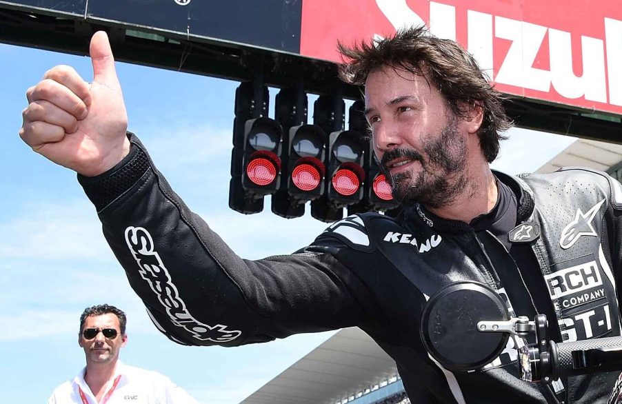 Keanu Reeves riding a motorcycle giving thumbs up