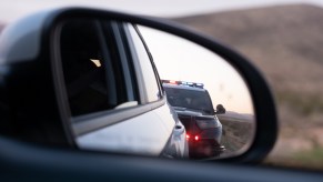 Police cruiser reflected in car's side view mirror depiction of getting a speeding ticket