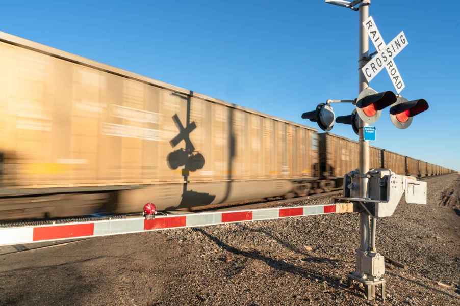 A moving freight train crossing with blue sky in background