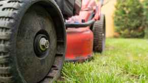 Riding lawn mower in close view of left front wheel and side