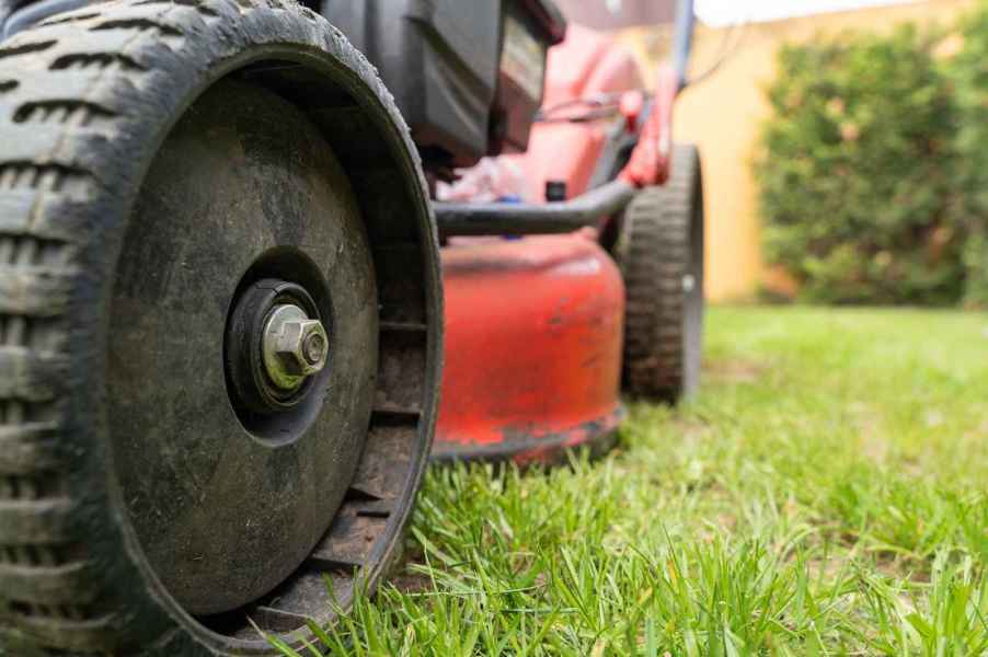 Riding lawn mower in close view of left front wheel and side