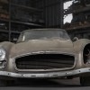 Unpainted Mercedes-Benz 300SL roadster supercar sitting in a barn, missing one headlight and grille.