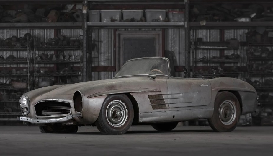 Side of a 1957 Mercedes-Benz roadster, unrestored, parked in a barn.