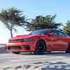 A red 2022 Dodge Charger Scat Pack Widebody driving near beach in left side angle view