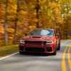 A rust-colored 2023 Dodge Charger Hellcat Redeye Widebody making 807 horsepower driving on a paved two-lane with fall trees in background