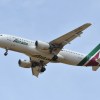 Alitalia airplane flying in front of a blue sky.