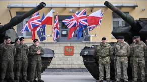 British soldiers standing at attending by their tanks.