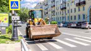 Bright yellow front-end loader driving on the road in Europe.