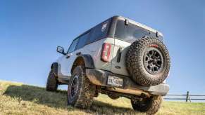 White Ford Bronco covered in mud and parked in a field off-road.