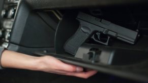 A driver reaches for a concealed handgun in a glovebox.